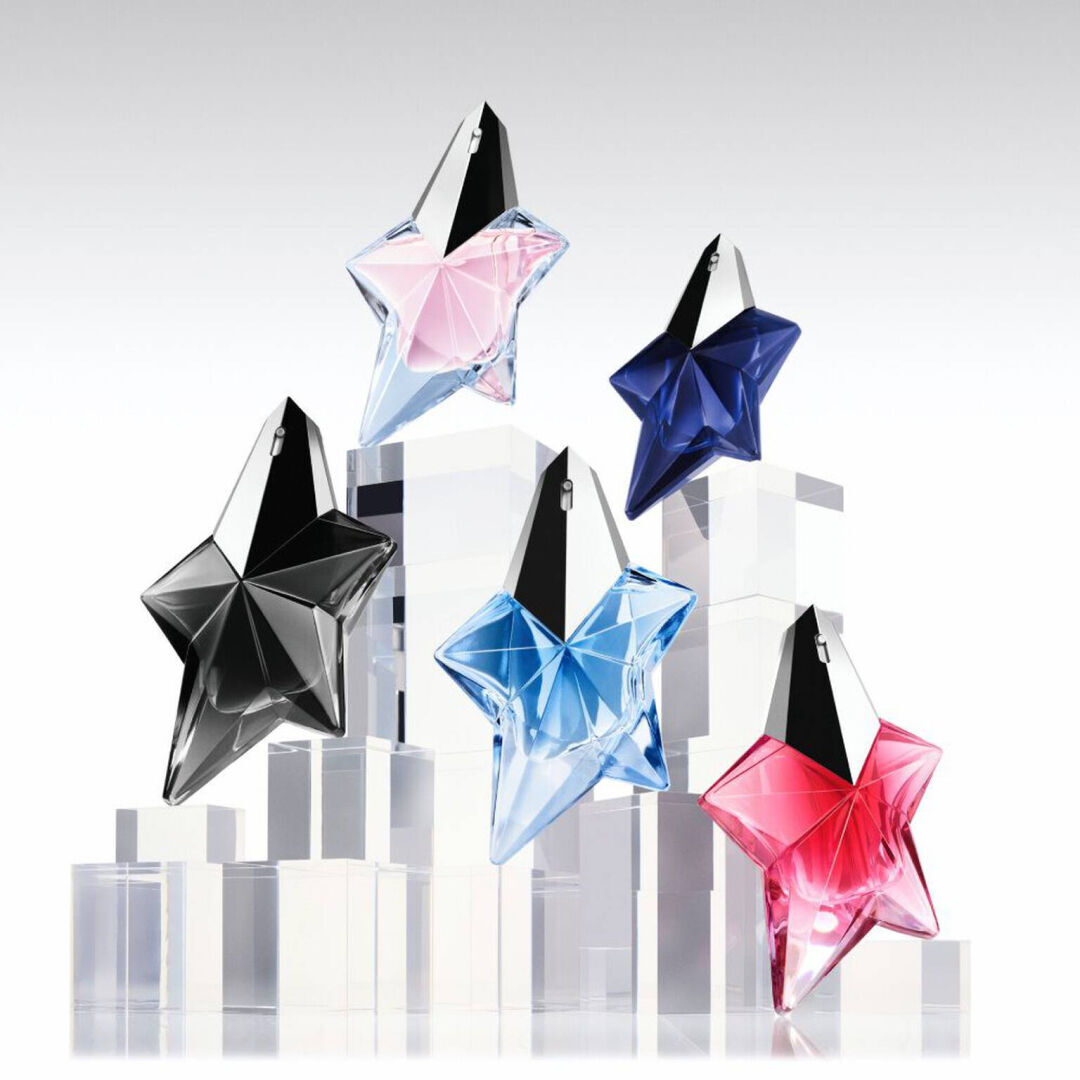 Five Mugler star perfume bottles in black, pink, blue, navy, and red on clear display blocks