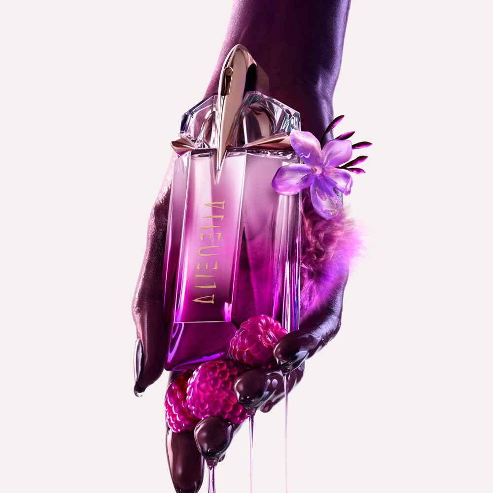  A hand gently holding the Mugler Alien Pulp bottle, with glistening pink berries and drips of liquid cascading from around it
