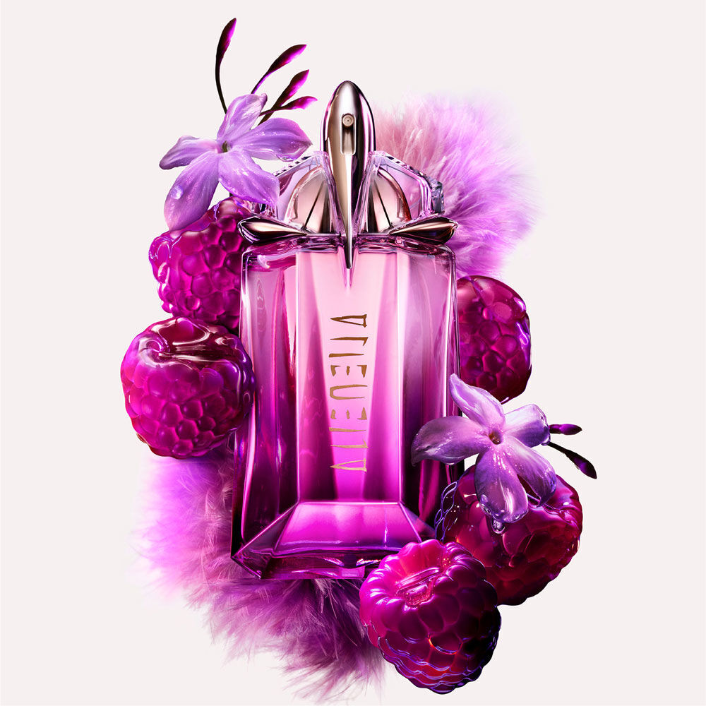Mugler Alien Pulp bottle amidst juicy pink berries, delicate purple flowers, and soft lavender feathers