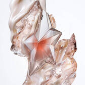 The Angel Blush star bottle surrounded by creamy almond milk swirls, textured sandalwood, and radiant musks, illustrating the fragrance's key olfactory notes.