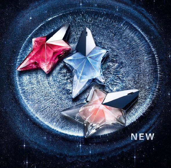 Three Mugler Angel star-shaped perfume bottles in pink, blue, and peach, displayed on a shimmering silver crater surface against a starry night sky background with the word ‘NEW.’