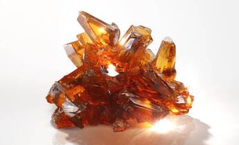 A cluster of sparkling amber crystals arranged in a jagged formation, illuminated from below to enhance their transparency and shine.