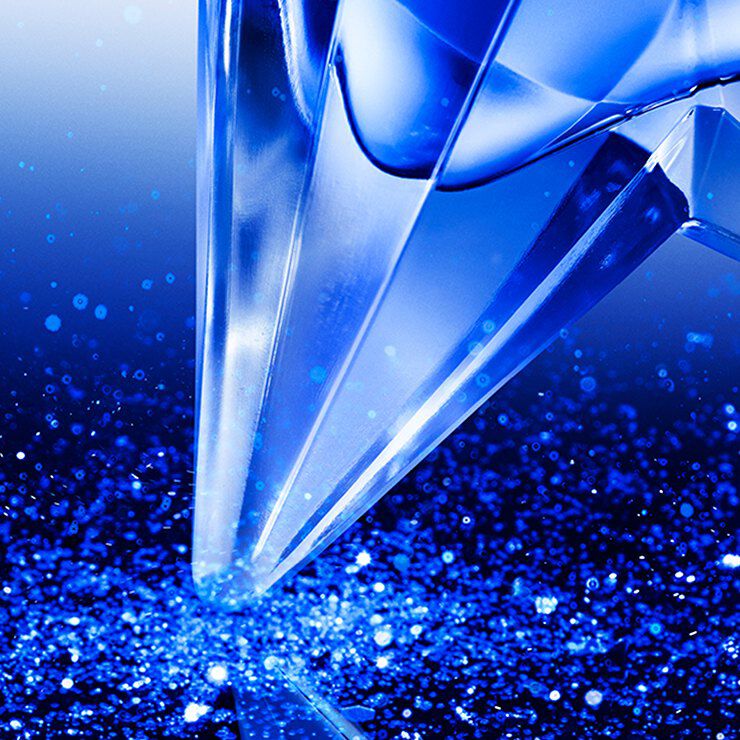 Close-up of the Angel Stellar eau de parfum bottle, glistening on a dark blue glittery surface