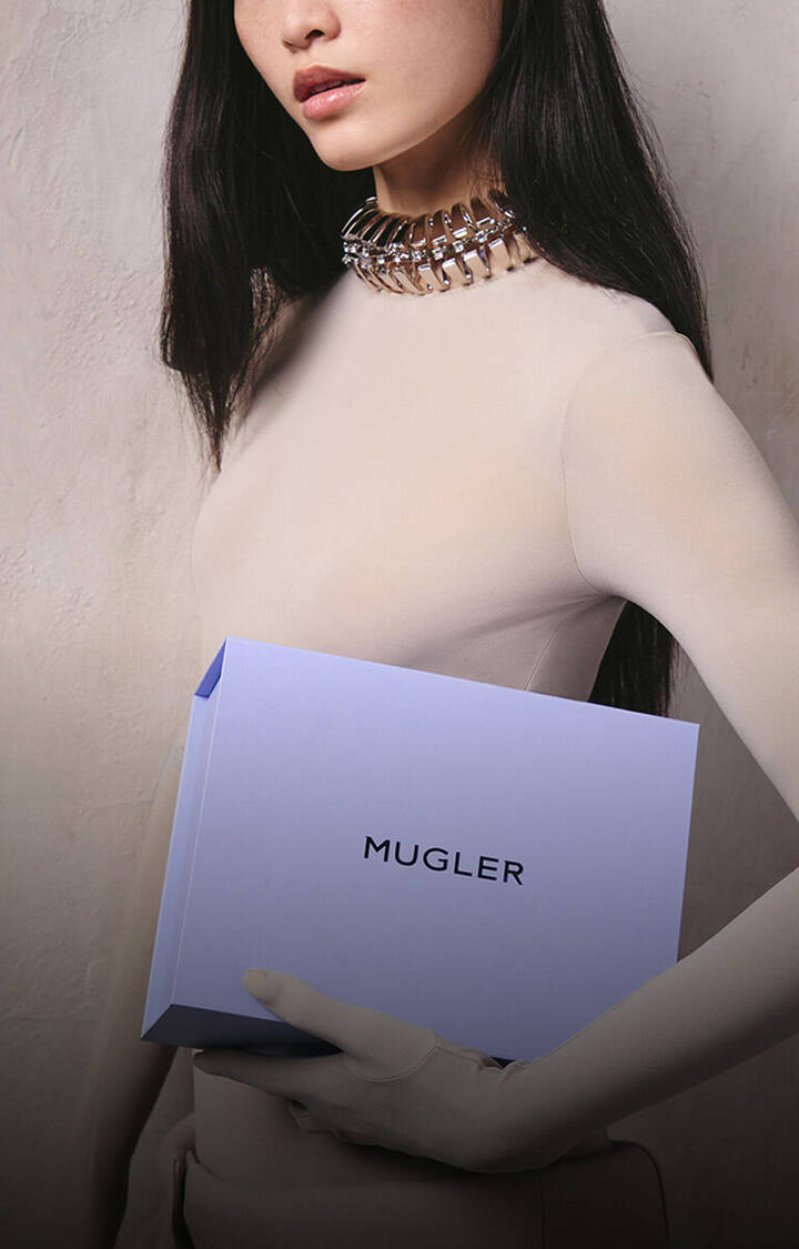 Model holding a Mugler gift box and loyalty envelope representing reward points per purchase.