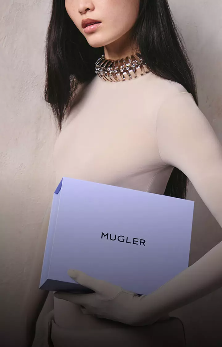 Model holding a Mugler gift box and loyalty envelope representing reward points per purchase.