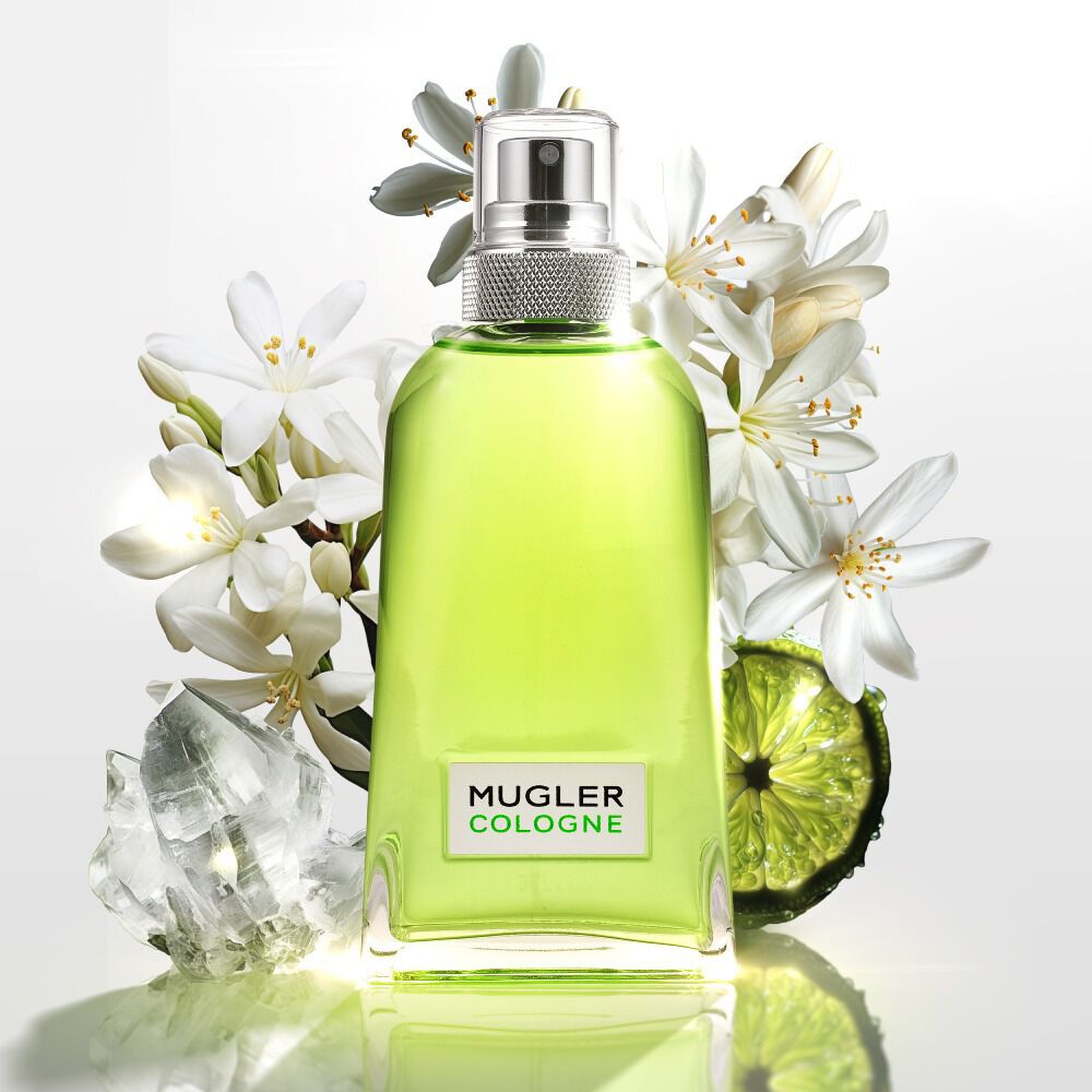 Mugler Cologne perfume bottle, white flowers, lime slice, and crystals.