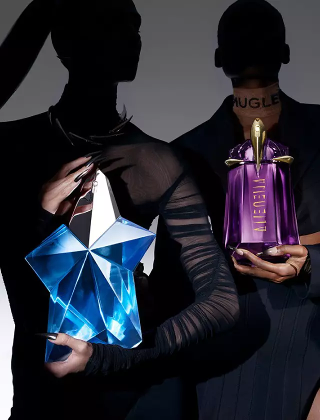 Two silhouettes of models holding distinctive perfume bottles, one with a blue star-shaped bottle and the other with a purple bottle. The background is a gradient from dark to light.