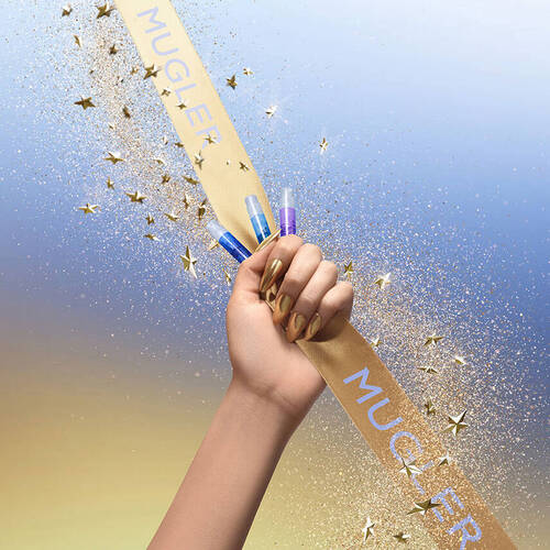 A hand with long, golden metallic nails clutches a gold ribbon with 'MUGLER' printed on it,
            while holding three small perfume samples in shades of blue and purple. Golden glitter and star-shaped
            confetti fall around the hand against a gradient background of blue and gold.