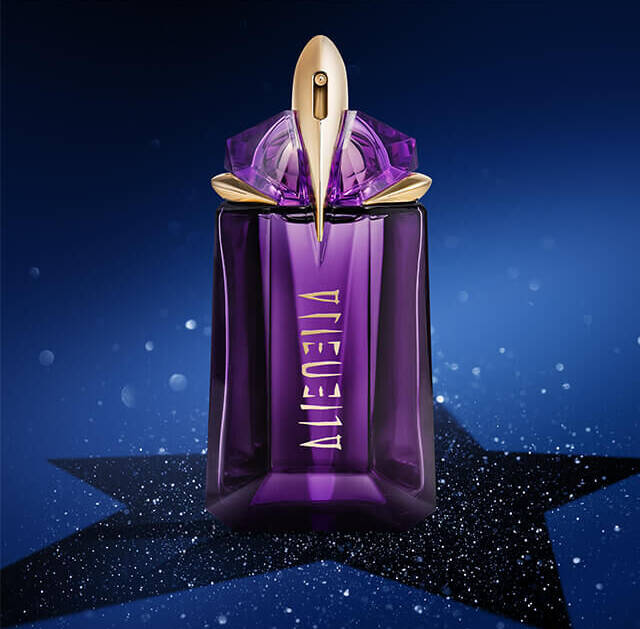A bottle of perfume with a striking purple design, topped with a golden cap, is displayed against a dark blue starry background.