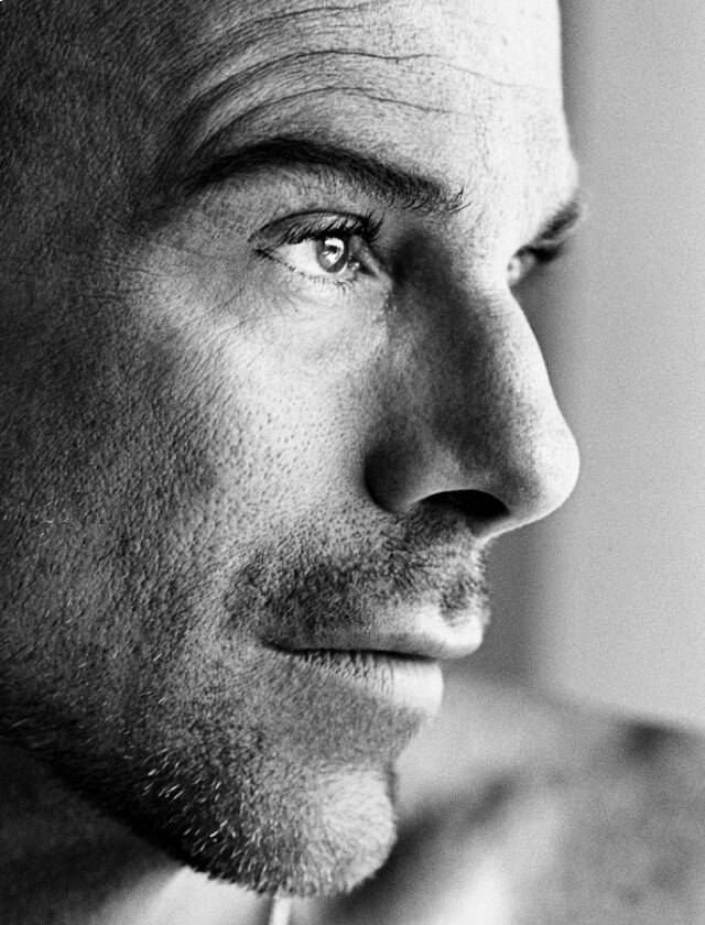A close-up black and white profile portrait of a man with a thoughtful expression.