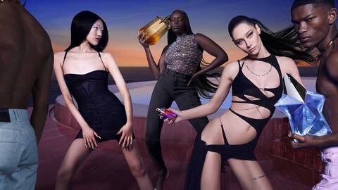 A group of four stylish individuals poses against a vibrant sunset backdrop, showcasing fashionable outfits and accessories. One holds a large perfume bottle while others display playful poses, emphasizing confidence and glamour.