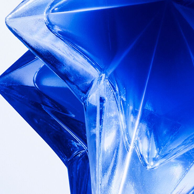 Close-up of the star-shaped Angel Stellar eau de parfum bottle on a glittery background