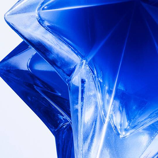 Close-up of the star-shaped Angel Stellar eau de parfum bottle on a glittery background