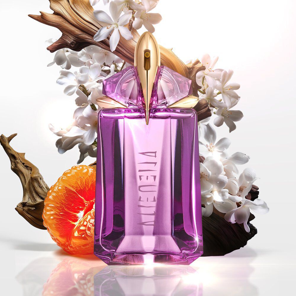 Purple Alien perfume bottle, white flowers, wood, and orange slice.