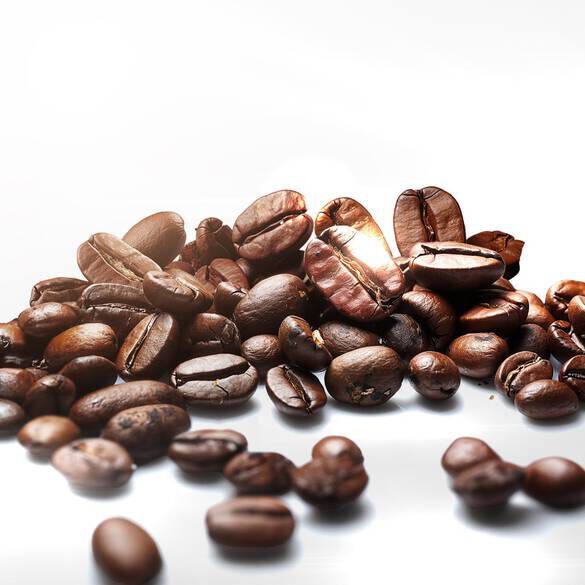 A pile of various coffee beans on a reflective surface, showcasing their rich brown colors and different shapes.