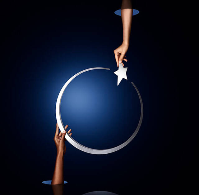 A hand reaches to place a star onto a crescent moon against a dark blue background.