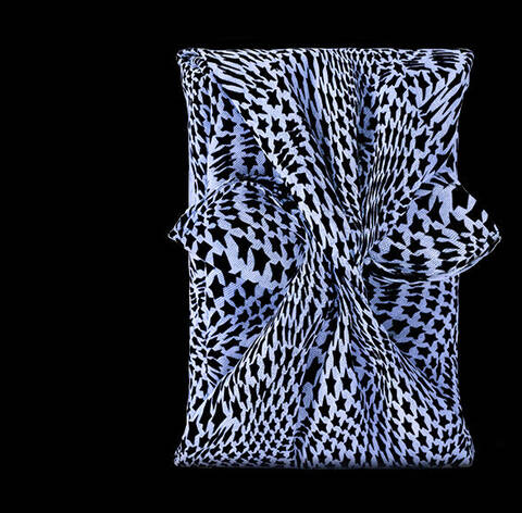 A stylized blue star-shaped perfume bottle next to an elegantly patterned fabric pouch against a black background.