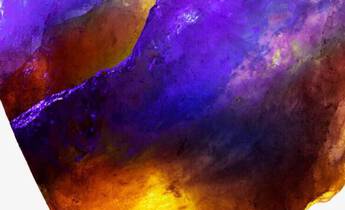 A large, multifaceted crystal displaying a vibrant gradient of purple, orange, and yellow hues.