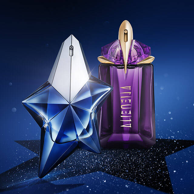 Two elegant perfume bottles are displayed against a dark blue background with sparkling stars. The left bottle is shaped like a blue star, while the right bottle has a purple, tall design.