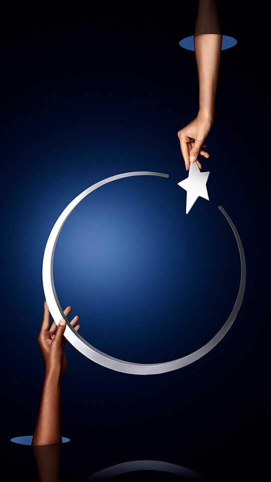 A hand reaches to place a star onto a silver crescent moon against a deep blue background.