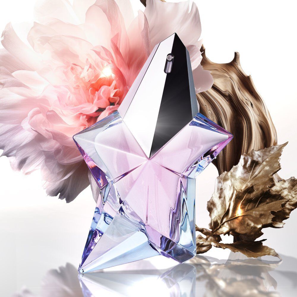 Pink and blue star-shaped perfume, with a pink flower, wood, and a golden leaf.