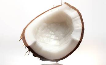 A freshly cut coconut half, showcasing its white flesh and inner texture, with a soft light illuminating it from behind.