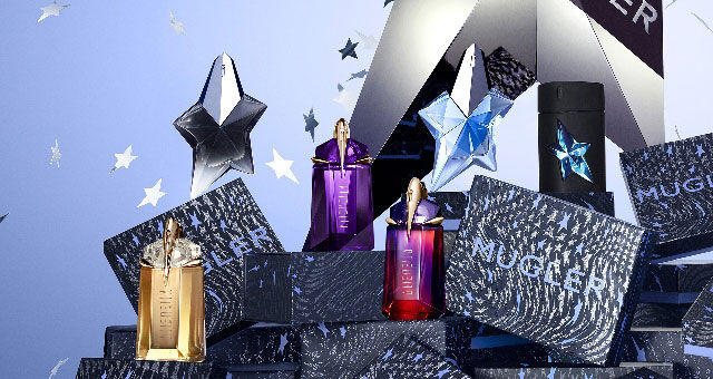 A collection of colorful perfume bottles shaped like stars, displayed alongside elegant packaging, set against a backdrop of shimmering stars.