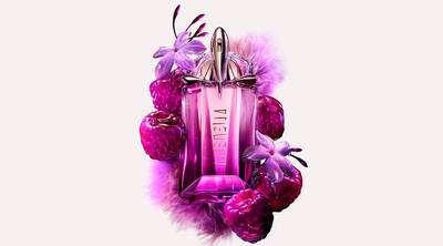 A vibrant, pink and purple perfume bottle for Mugler's Alien Hypersense is centered amidst raspberries, purple flowers, and soft, fuzzy textures.