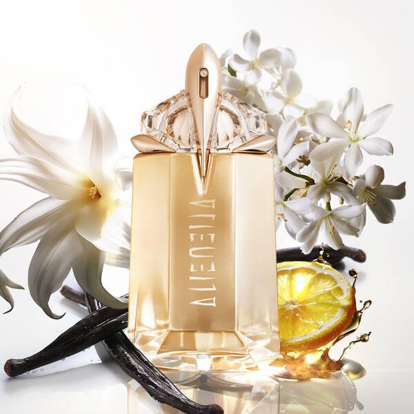 Golden Alien perfume bottle with white flowers, vanilla, and a lemon slice.