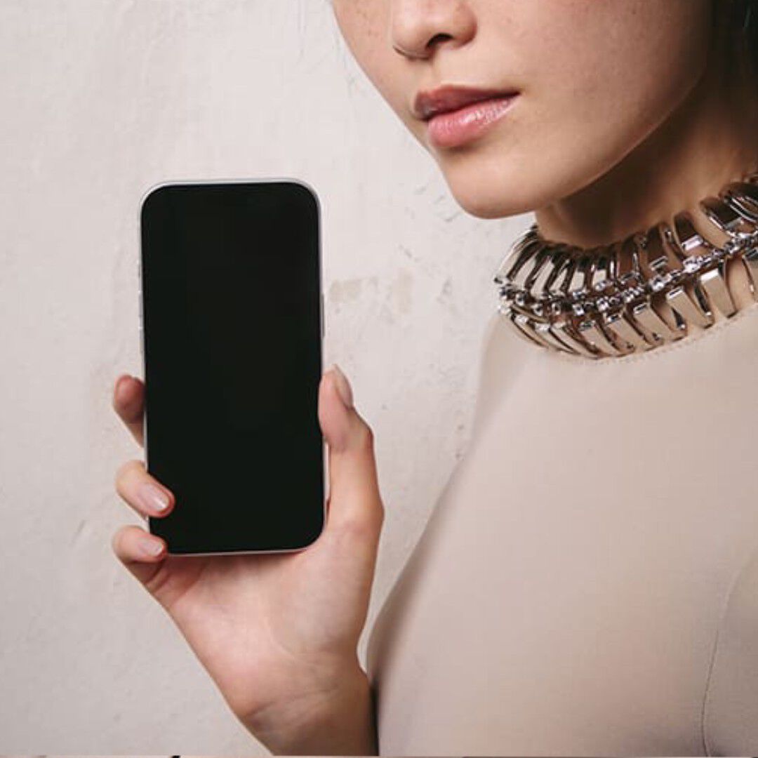Close-up of model holding a smartphone with a blank screen.​