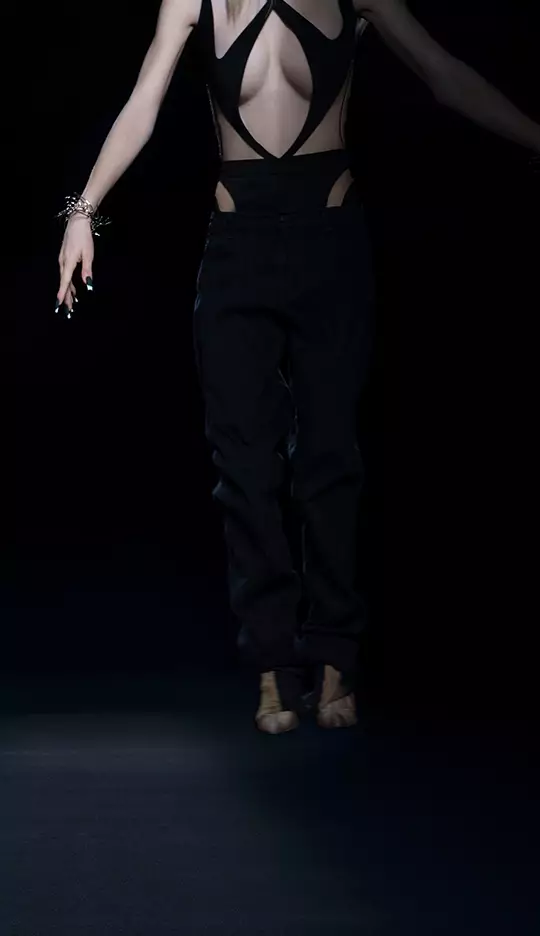 A person is wearing a stylish, revealing outfit with cut-out details, and is depicted mid-jump against a dark background, emphasizing their silhouette.