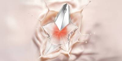 A star-shaped glass perfume bottle with a silver cap splashing into a smooth, creamy pink liquid.