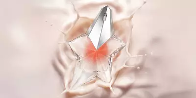 A star-shaped glass perfume bottle with a silver cap splashing into a smooth, creamy pink liquid.