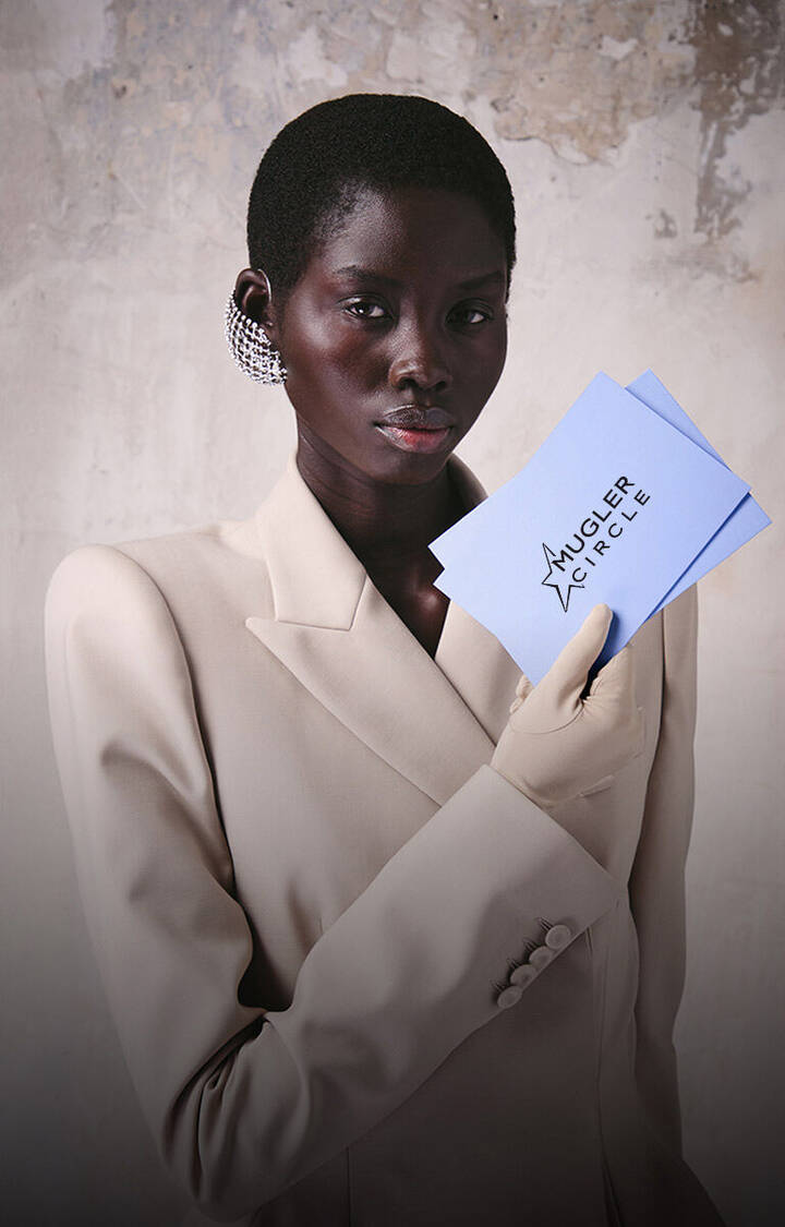Model holding a Mugler birthday gift envelope and card.