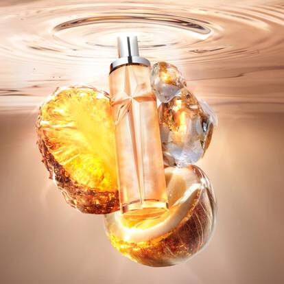 A orange star-shaped perfume bottle floating in water with pineapple and coconut