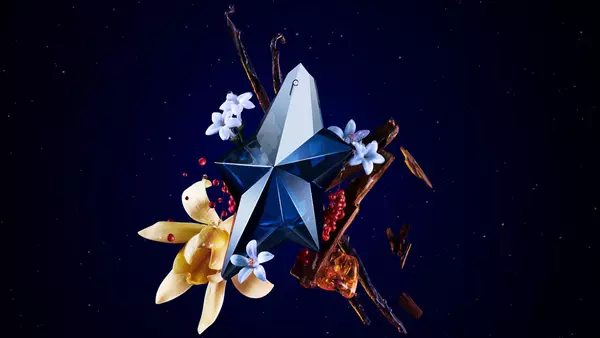 Visual of the "Angel Elixir" perfume featuring a striking blue and silver bottle surrounded by flowers, spices, and artistic elements on a dark starry background. Text reads "ANGEL ELIXIR" and "THE NEW FRAGRANCE."