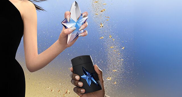 Angel Mugler beauty products on a glittery gold background with star accents.