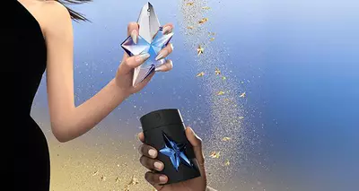 Angel Mugler beauty products on a glittery gold background with star accents.