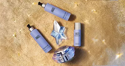 Angel Mugler beauty products on a glittery gold background with star accents.