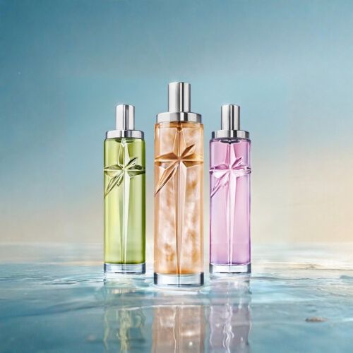 Three slender glass perfume bottles in green, gold, and purple standing on a reflective wet surface under a light blue sky.