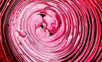 Close-up image of a vibrant red and pink abstract swirl, resembling smooth waves or ripples in a fluid.