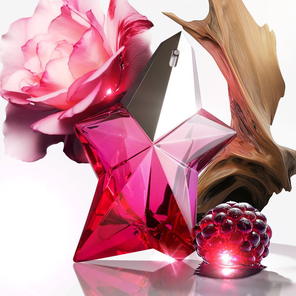 A striking pink star-shaped perfume bottle surrounded by a rose and artistic wooden elements, creating an elegant, floral display.