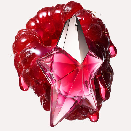 A star-shaped pink metallic perfume bottle positioned over a glossy, melting red raspberry.