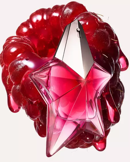 A star-shaped pink metallic perfume bottle positioned over a glossy, melting red raspberry.