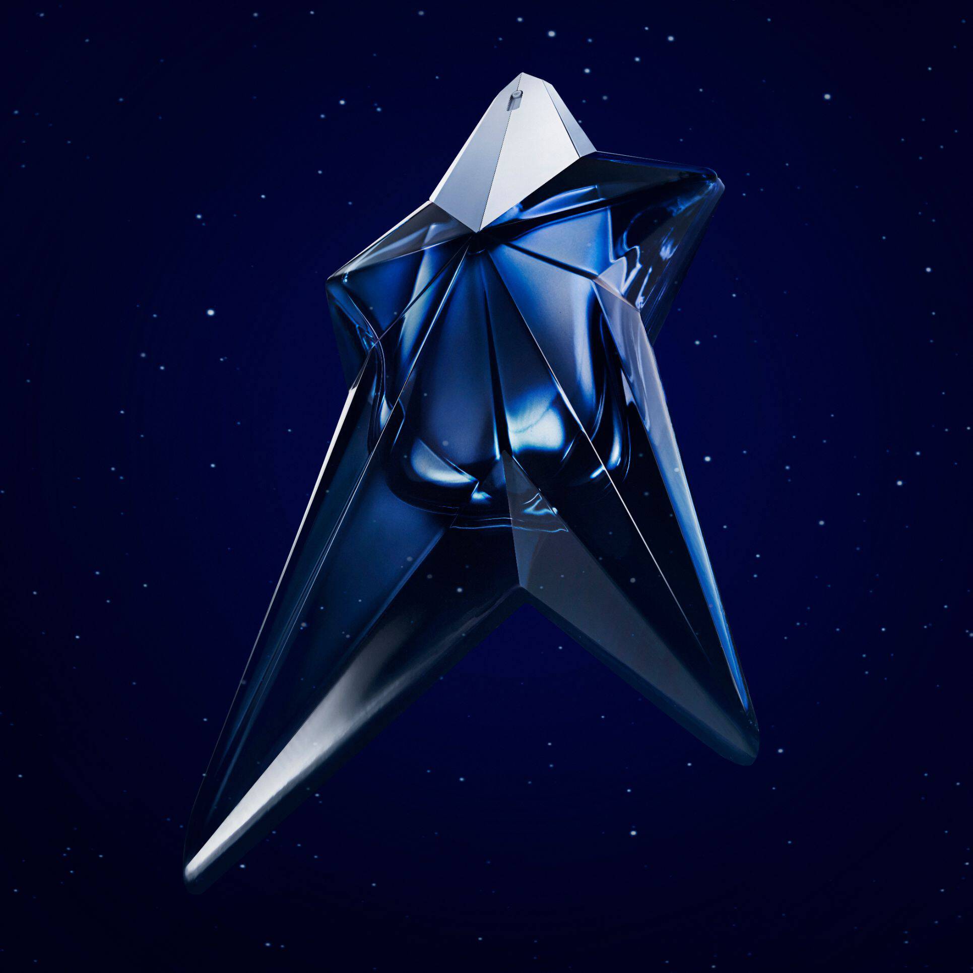 Alt text: A five-point star-shaped perfume bottle in a deep blue hue, set against a dark starry background, with text announcing the birth of a new fragrance from Mugler.