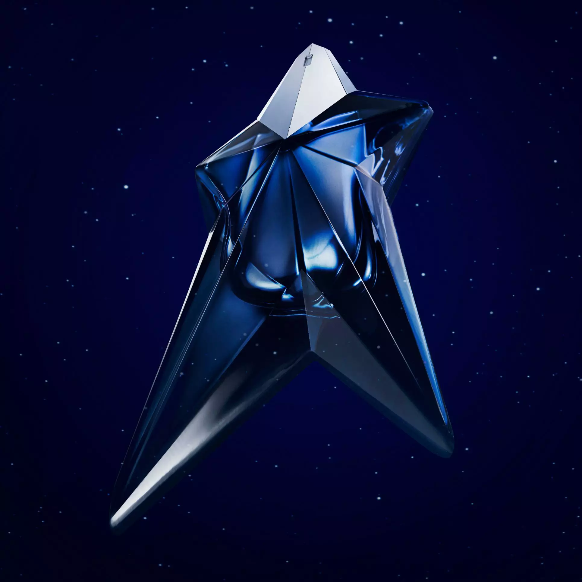 Alt text: A five-point star-shaped perfume bottle in a deep blue hue, set against a dark starry background, with text announcing the birth of a new fragrance from Mugler.
