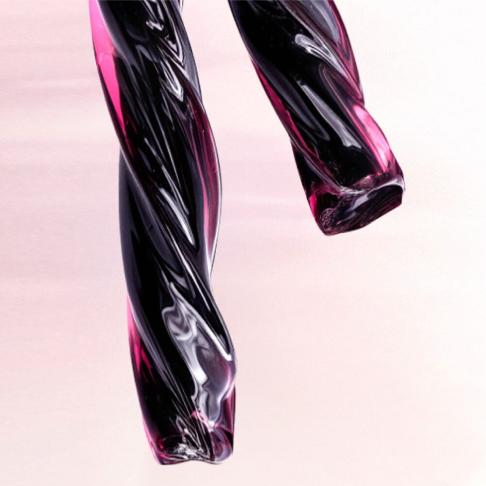 A close-up of two twisted, glossy strands of deep purple and black material resembling licorice. The text describes this as a deep licorice accord that adds contrast and intensity, anchoring the composition of the scent.