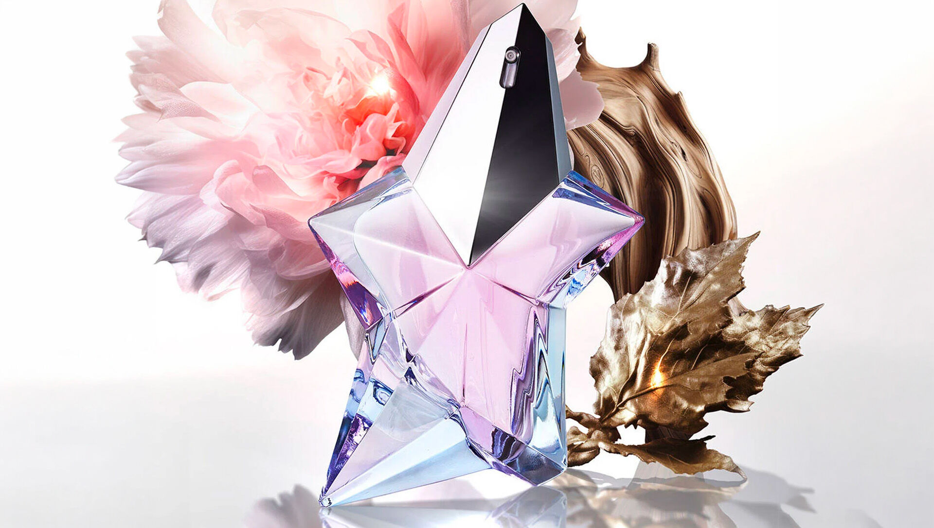 Mugler Angel Eau de Toilette star-shaped bottle surrounded by pink peony flower and golden woody elements, showcasing key floral and warm fragrance notes
