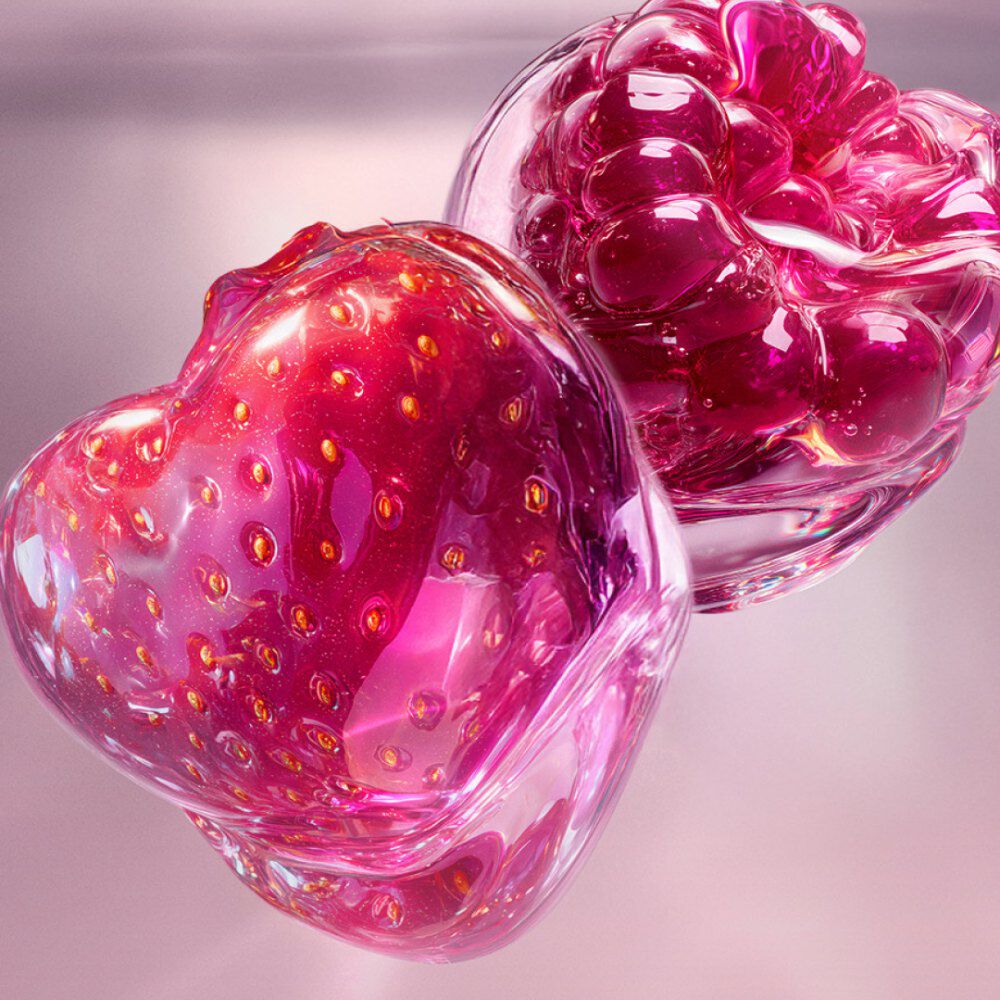 A close-up of a strawberry and a raspberry, both encased in glossy, jewel-like translucent shells in shades of vibrant pink and deep red. The text describes it as a tender strawberry and sparkling raspberry combination that brings juicy, vibrant sweetness.