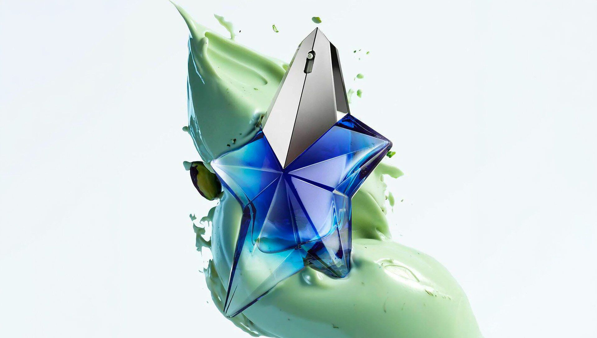 Mugler Angel Stellar electric blue star-shaped bottle on fresh green background, showcasing key fragrance ingredients
